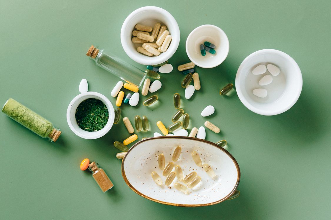 Unbranded vitamins and wellbeing supplements arranged on a green surface